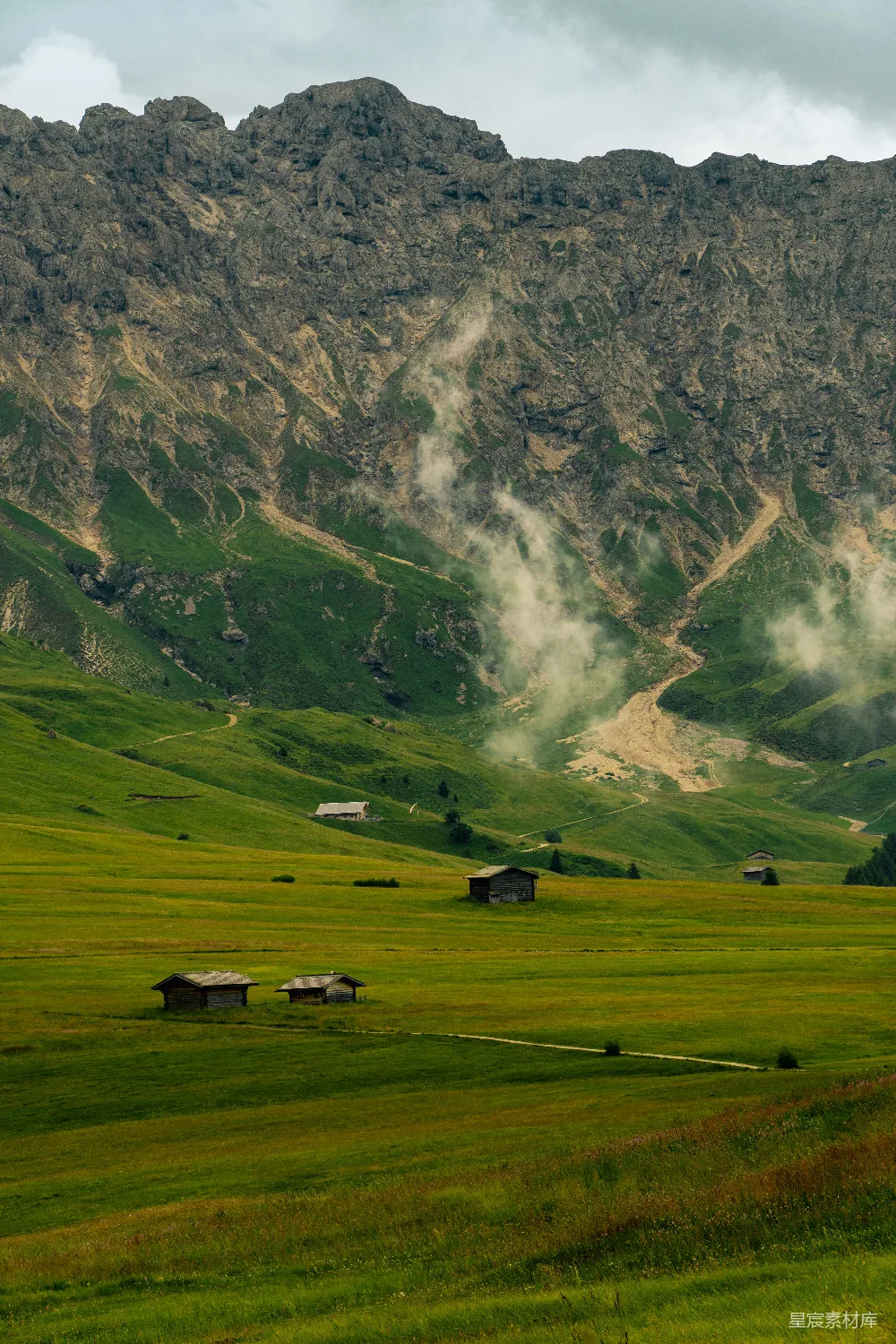 高清摄影  绿草如茵的草地和连绵的山脉，山间还有小木屋。