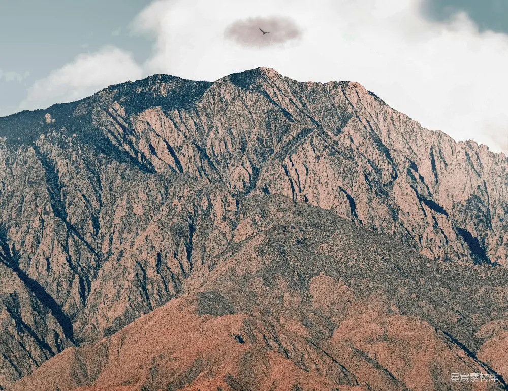 高清摄影  白天，白云飘浮在棕色岩石山下。