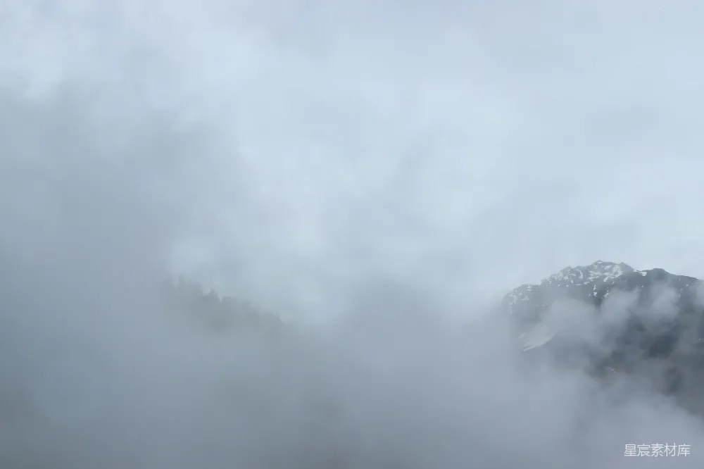 高清摄影  多云天空下，山脉被浓雾覆盖。