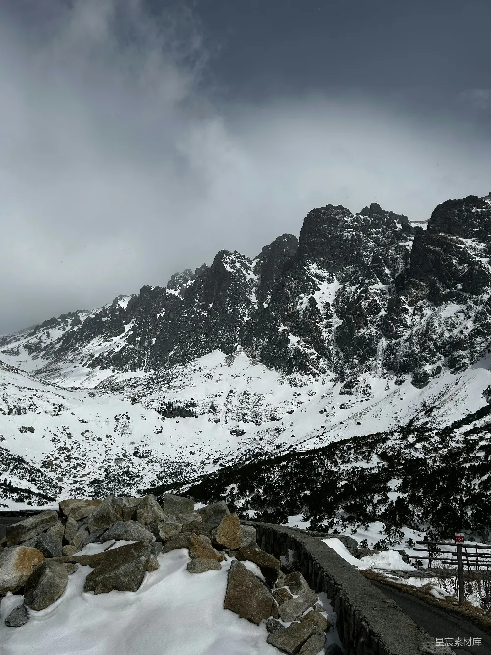 高清摄影  云层密布的天空下覆盖着积雪的山峰。