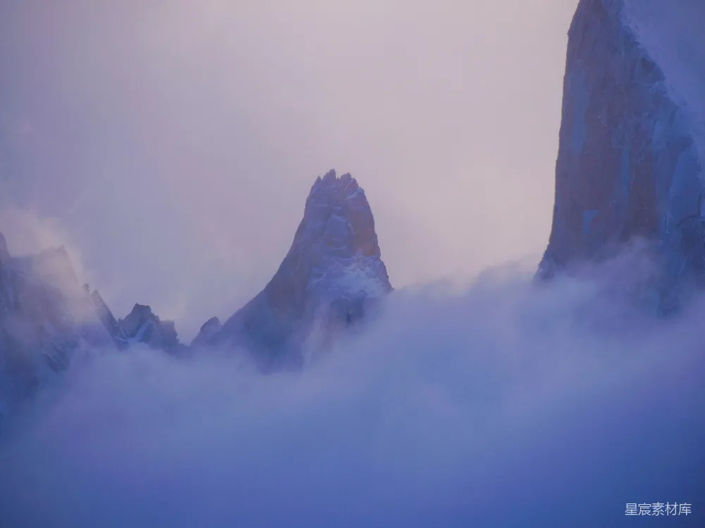 高清摄影  一座被雪和云覆盖的山峰，背景是蓝天。