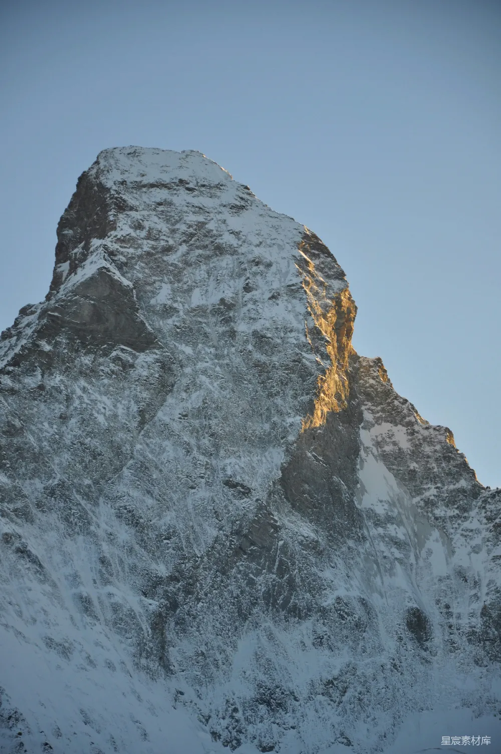 高清摄影  白雪覆盖的山峰，一侧沐浴在金色阳光下。