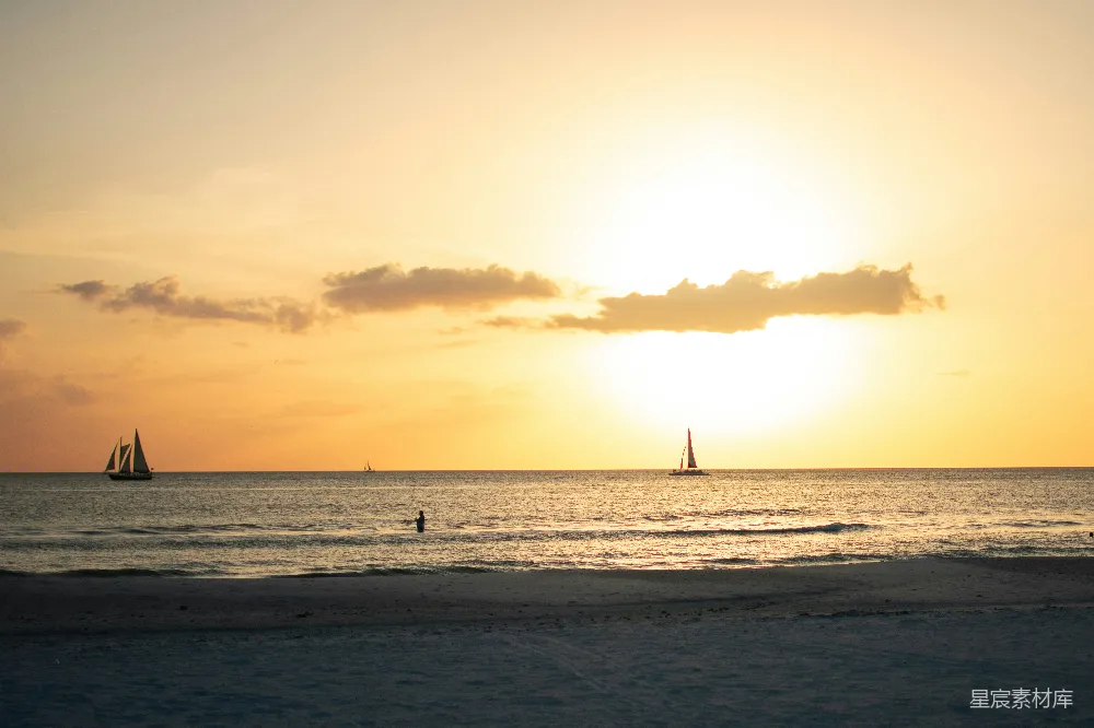 高清摄影 自然 夕阳正照耀着海面，远处可以看到几艘帆船。