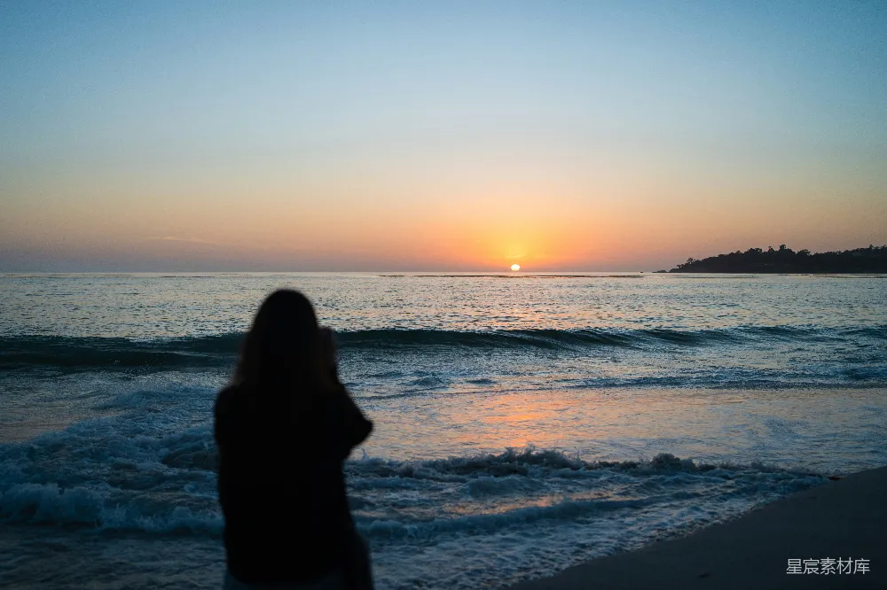 高清摄影 自然 人物 一位女士站在海滩上，夕阳西下。