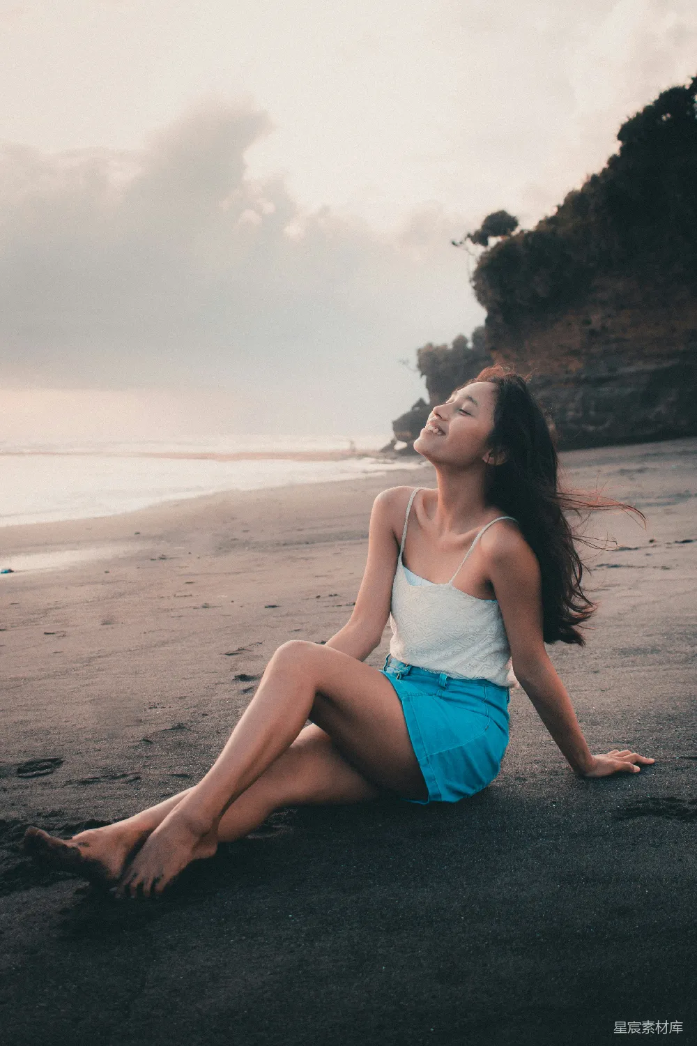 高清摄影  穿着蓝色牛仔短裤的女人坐在海滩岸边，白天。