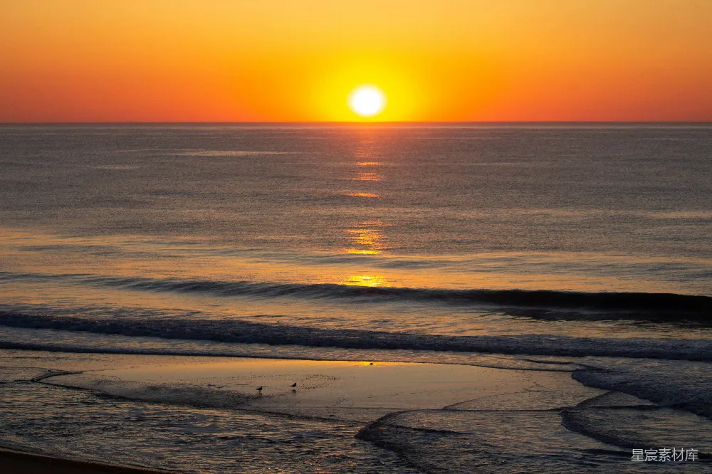 高清摄影 自然 夕阳正洒落在海滩上空的海面上。