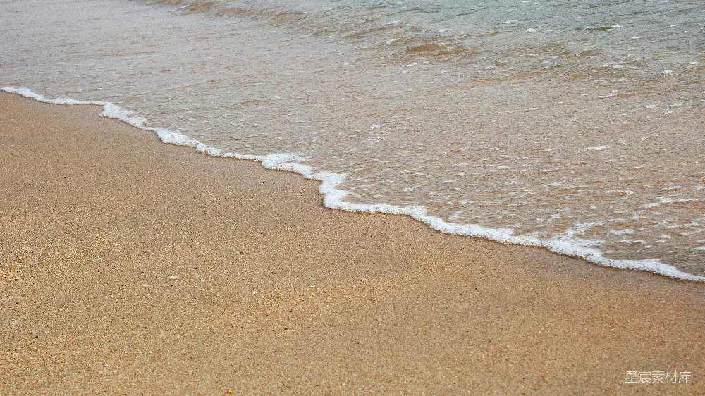 高清摄影  一个沙滩上有海浪拍打岸边。