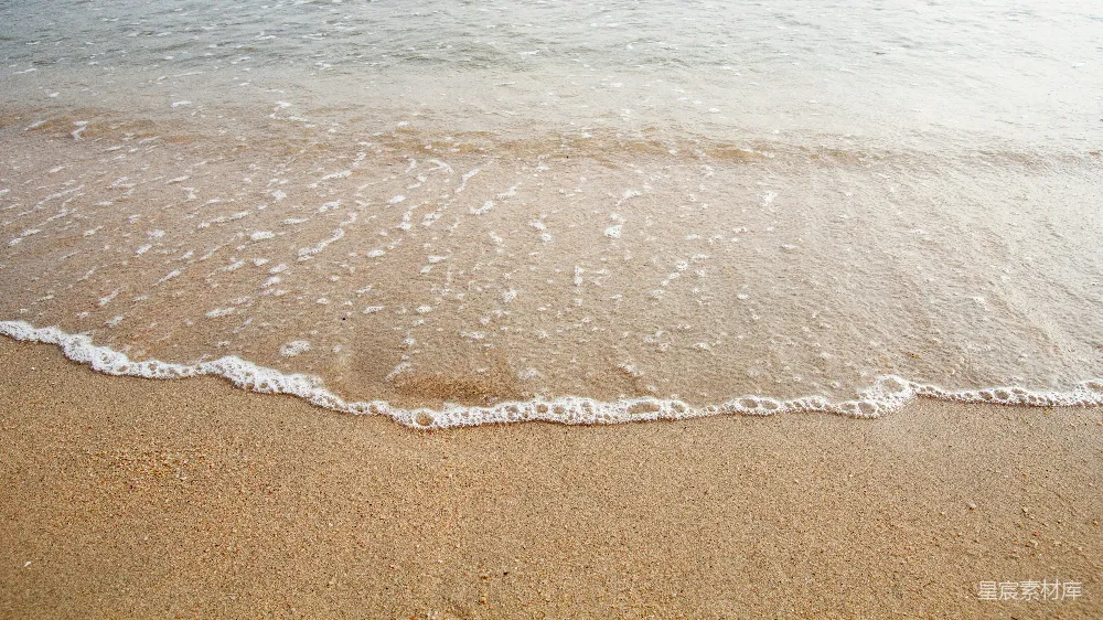 高清摄影  一个沙滩，海浪拍打着岸边。