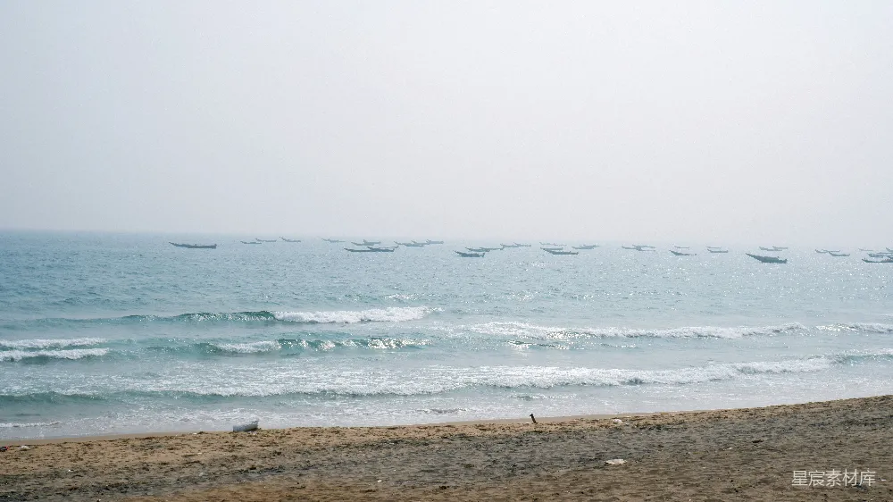 高清摄影  平静的海面上，船只在薄雾笼罩的天空下漂浮。