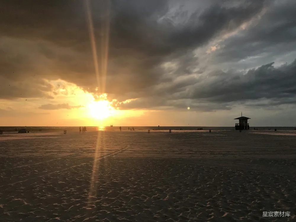 高清摄影 夕阳西下，海滩上有人影。