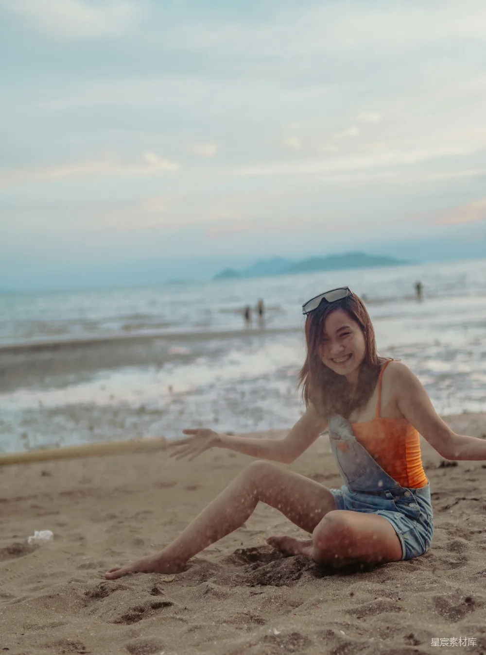 高清摄影  穿着红白比基尼的女子在白天坐在海滩岸边。