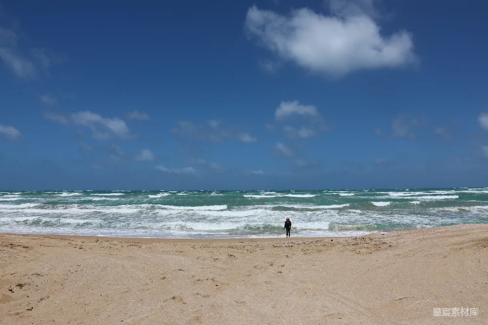 高清摄影  站在海滩上，靠近海洋旁边的人