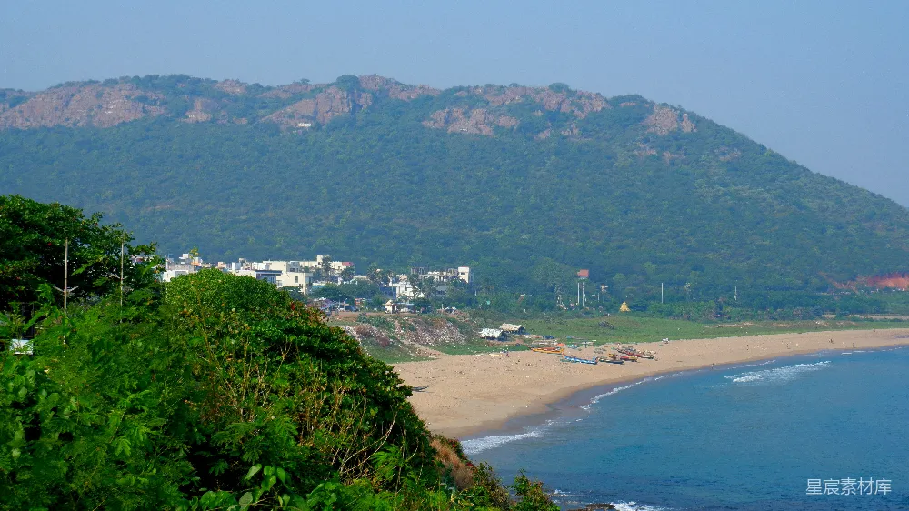 高清摄影  一个海滩场景，有山脉和建筑物。