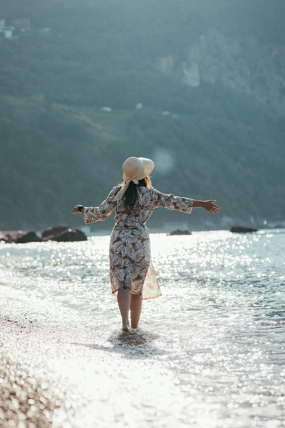 高清摄影  一个女人沿着海滩散步，海浪拍打着岸边。