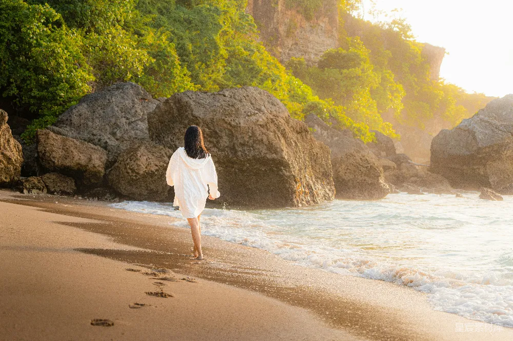 高清摄影  一位女士在海滩上散步，海浪拍打着岸边。