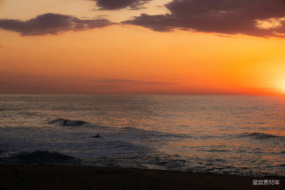 高清摄影  夕阳照耀下的海洋，一个冲浪者在水中
