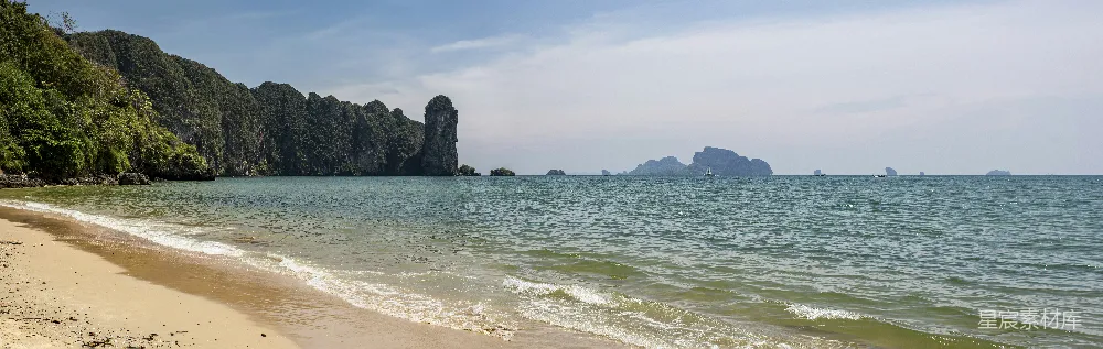 高清摄影  一个沙滩紧邻大海，背景中有山脉。
