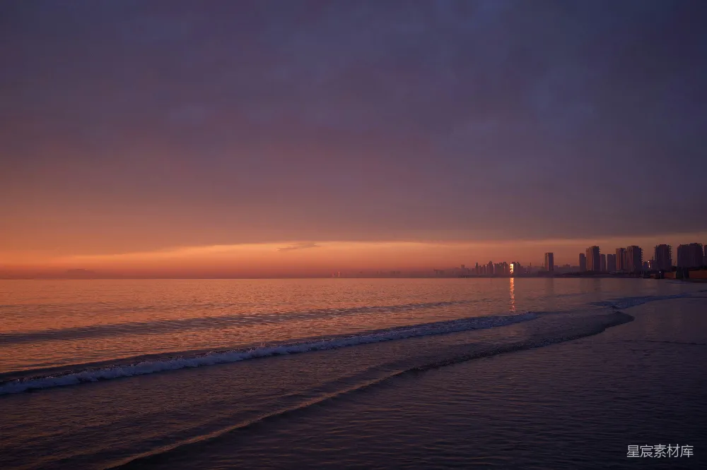 高清摄影  夕阳西下，海滩景色迷人，远处隐约可见一座城市。
