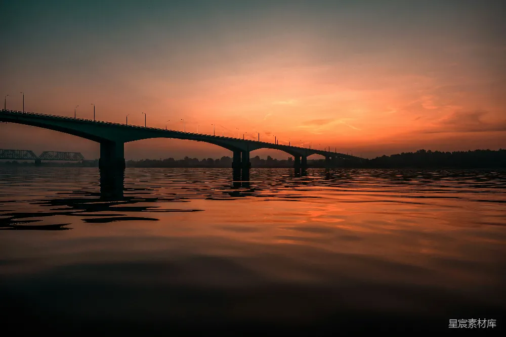 高清摄影  混凝土桥下，橙色的天空映衬着海景。