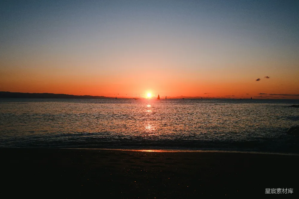 高清摄影  夕阳正缓缓地沉落在海滩的海面上。