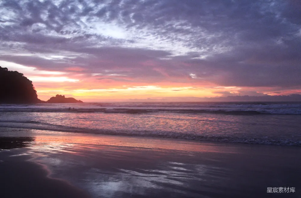 高清摄影  夕阳在海滩上落下，海浪拍打着岸边。