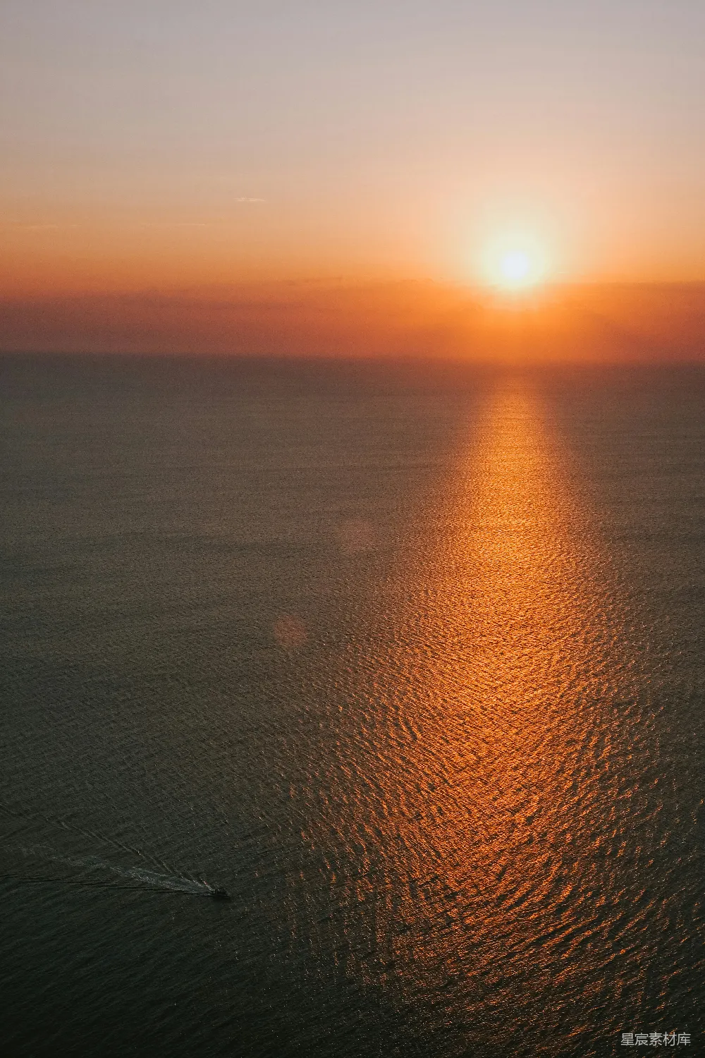 高清摄影  夕阳照耀着平静的海洋，远处有一艘小船。