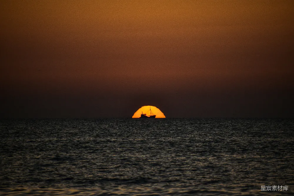 高清摄影 自然 夕阳正缓缓沉入海面，远处有一艘船。