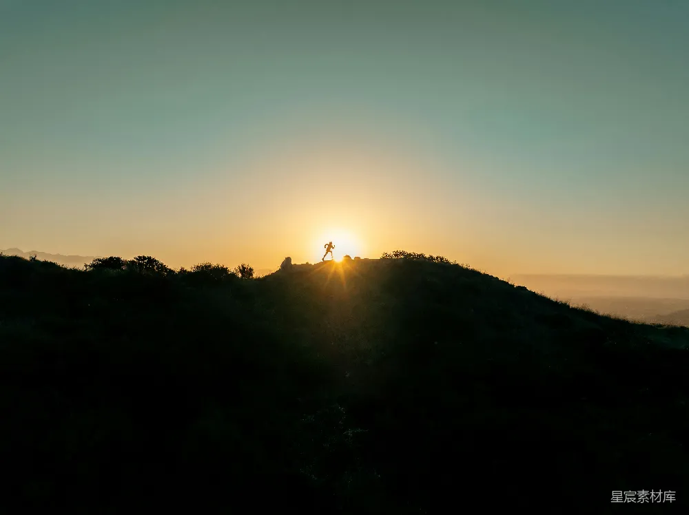 高清摄影  太阳正落在这座山丘上，上面有一个人。