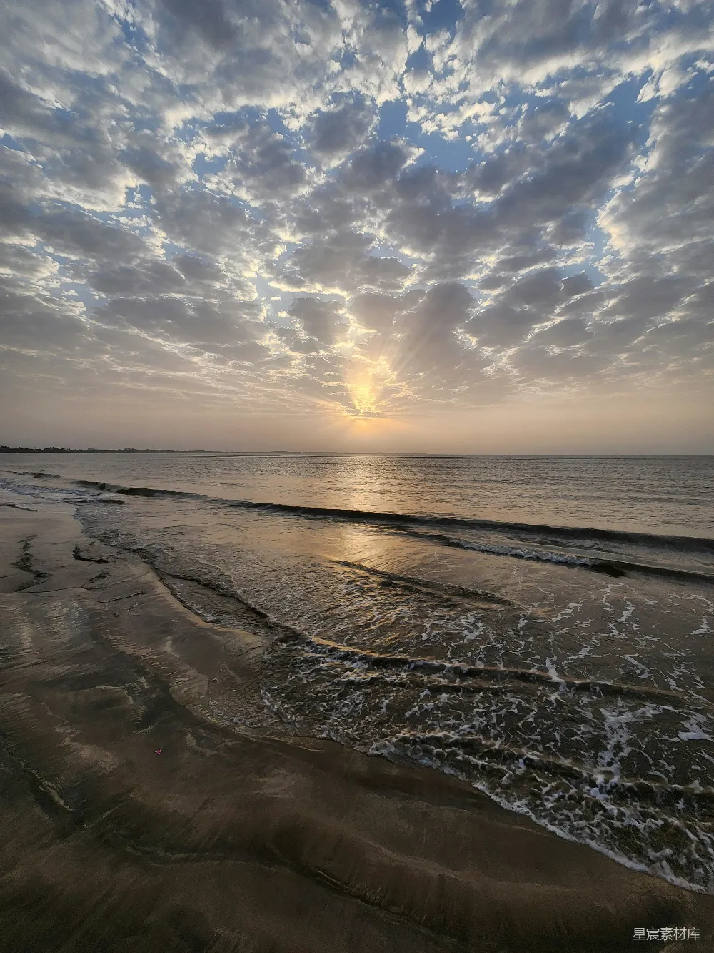 高清摄影  夕阳正挂在海平面上，海滩上。