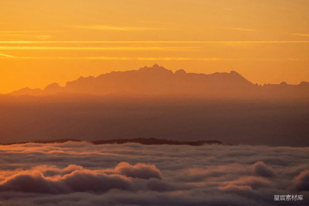 高清摄影  夕阳正从云层上方的山脉上落下