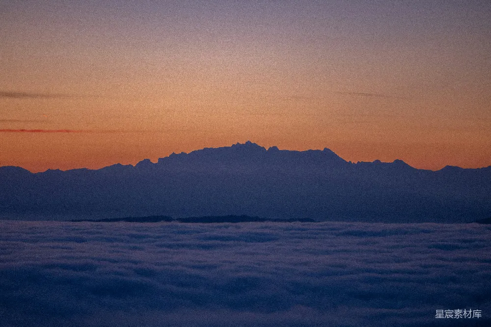 高清摄影  夕阳正照在云层上方的山峦之上。