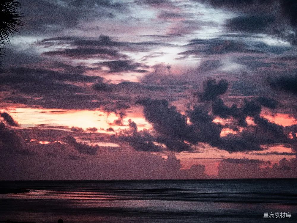 高清摄影  夕阳正洒落在海洋之上，天空中有云彩漂浮着。