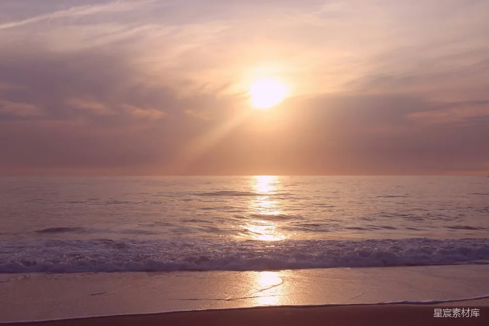 高清摄影  夕阳正洒落在海滩上的海洋上。