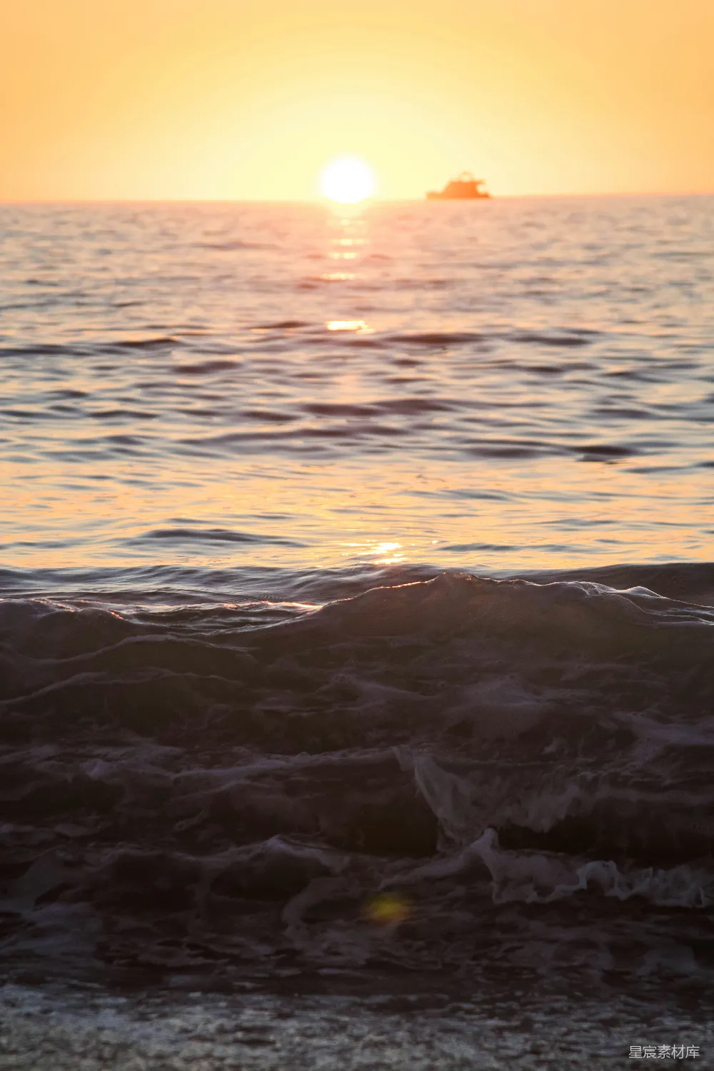 高清摄影  夕阳正缓缓沉入海面，远处有一艘小船。