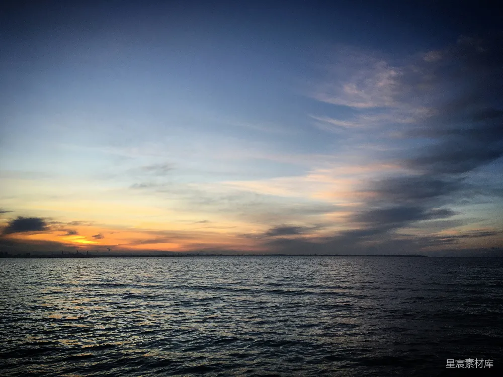 高清摄影  夕阳映照在水面上，天空中飘着云彩。
