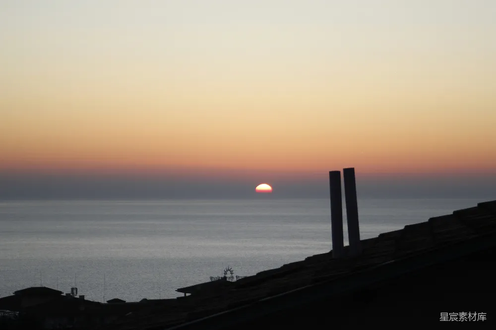 高清摄影  夕阳映照在海面上，屋顶的轮廓在天空中映衬而出。