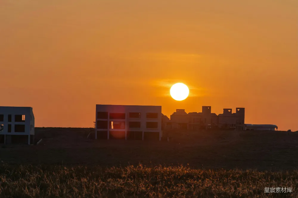 高清摄影  夕阳西下，草地上未完工的建筑物。