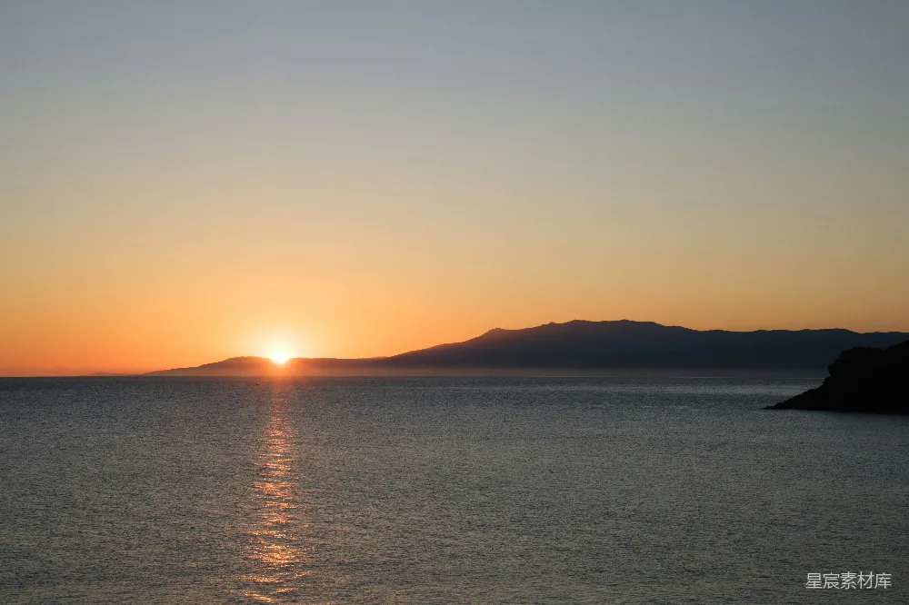 高清摄影  夕阳映照在海面上，远处的山脉若隐若现。