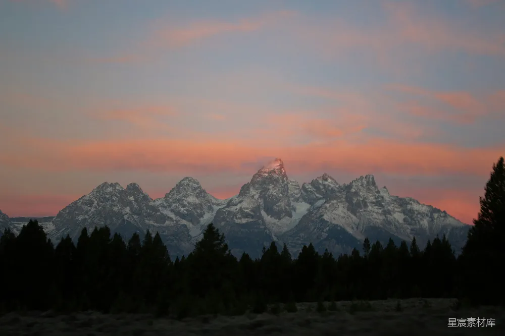 高清摄影  在山脉的夕阳景色中，前景中有树木。