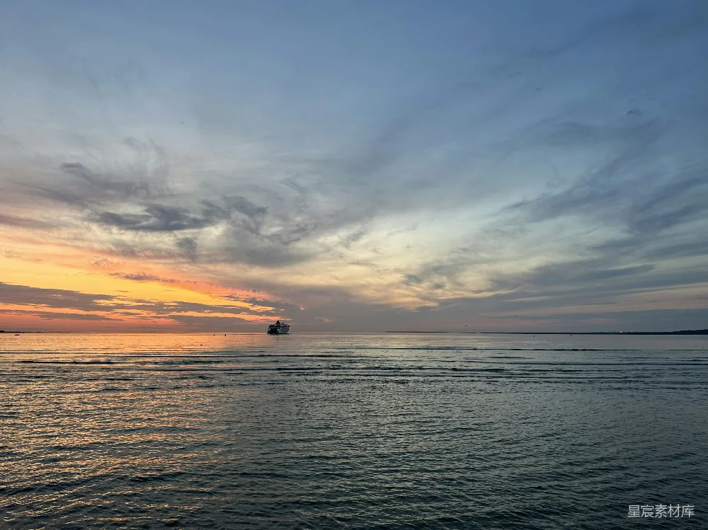 高清摄影  夕阳正映照着海面，远处有一艘小船。