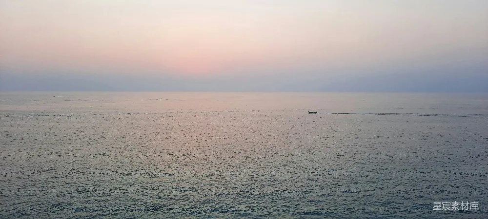 高清摄影  夕阳下，一艘小船在海面上航行。