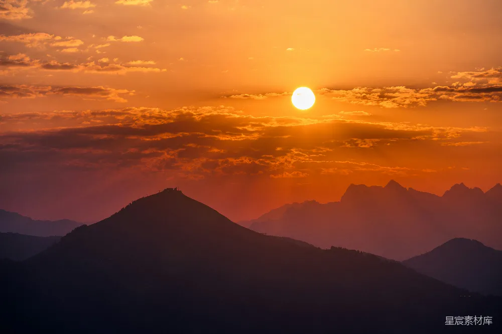 高清摄影  金黄色的夕阳落在剪影中的山峰后面。