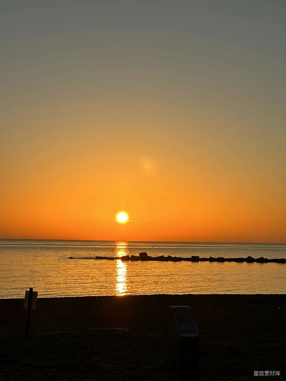 高清摄影  夕阳正挂在水边的海滩上。