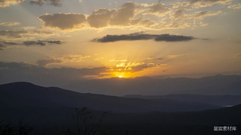 高清摄影  夕阳落山，映衬着轮廓鲜明的山脉，天空中布满了壮观的云彩。