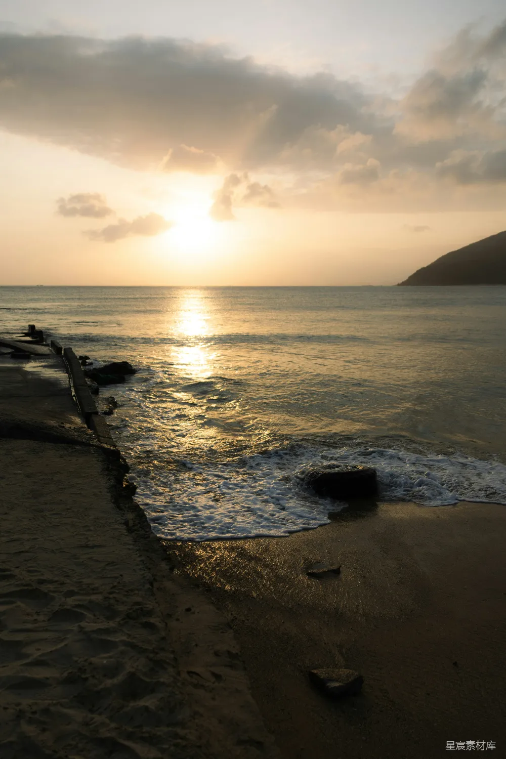 高清摄影  金色的夕阳洒在海洋上，波浪轻轻拍打着岸边。