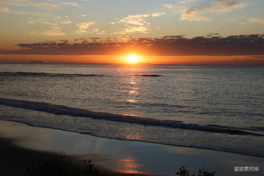 高清摄影  夕阳在海滩上空落下，照耀着海洋。