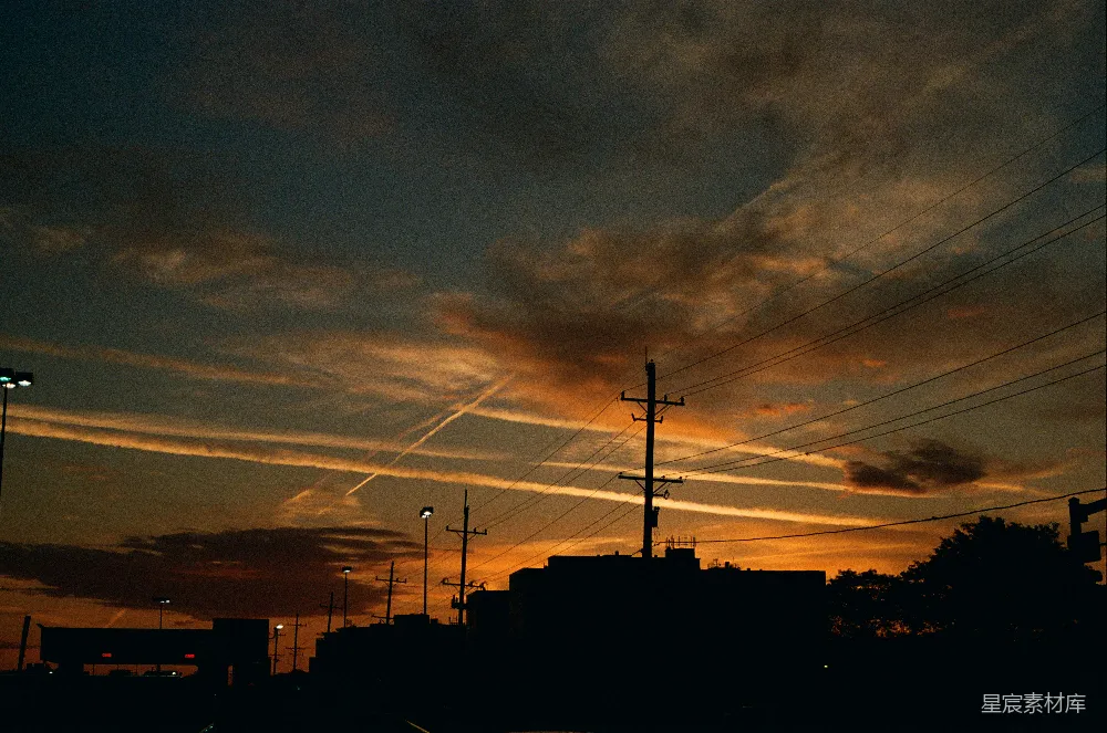 高清摄影  夕阳正照耀着一座城市，天空中有输电线路。