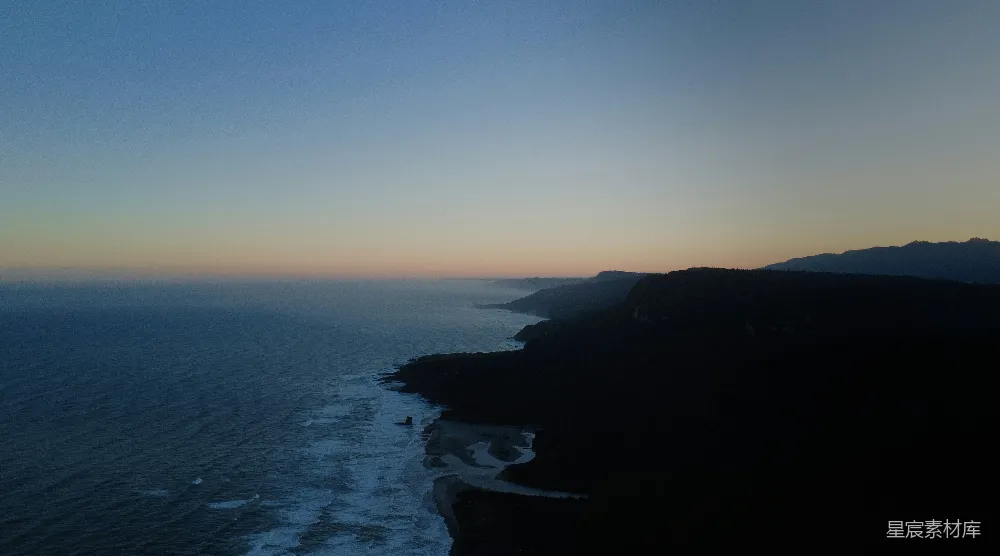 高清摄影  在黄昏时分，海浪拍打着一片黑暗而崎岖的海岸线。
