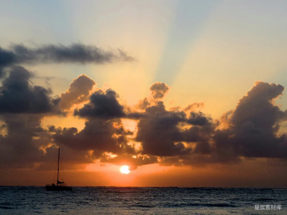 高清摄影  夕阳正落下海面，前景中有一艘帆船。