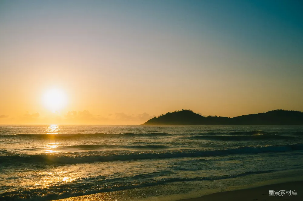 高清摄影  夕阳正缓缓落下，海面之上，远处有一座小岛。